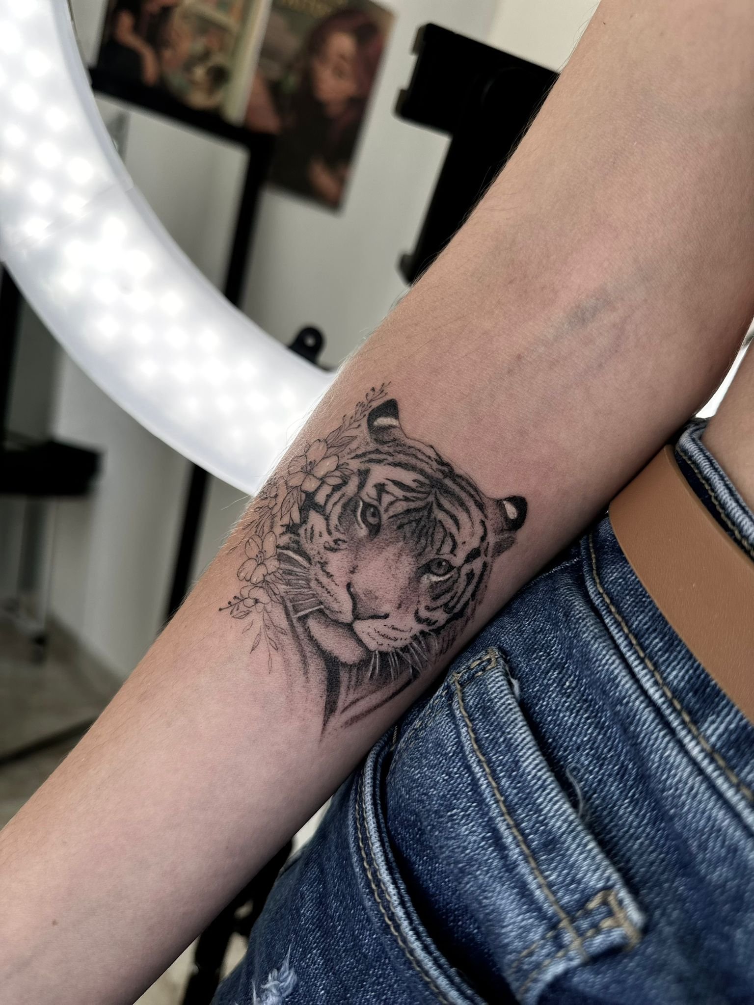 Tatuaje realista de cabeza de tigre en el antebrazo, en negro y gris con detalles de pelaje y sombreado.